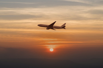 Beautiful transporation airplane is flying throught beautiful nature prime sun setting landscape warm tone background aswesome sky twilight silhouette.