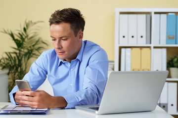 Young handsome businessman spending time on social media instead of working
