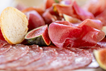 Light Italian snacks. A buffet table at a dinner party. Food tray with delicious salami, pieces of sliced ham, sausage. Cutting sausage and cured meat on a celebratory table.