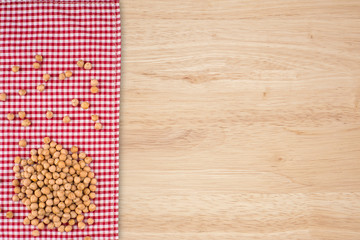 Chickpeas on a red napkin and old wooden table.