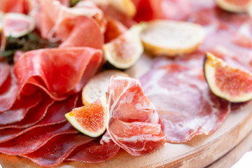 Light Italian snacks. A buffet table at a dinner party. Food tray with delicious salami, pieces of sliced ham, sausage. Cutting sausage and cured meat on a celebratory table.