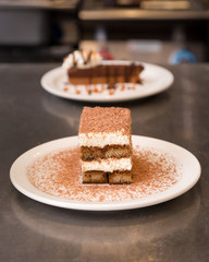 Tiramisu dusted with chocolate with a chocolate tart in the background.