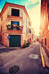 Fototapeta na wymiar Vintage stylized narrow street in Alcudia old town at sunset, Mallorca, Spain.
