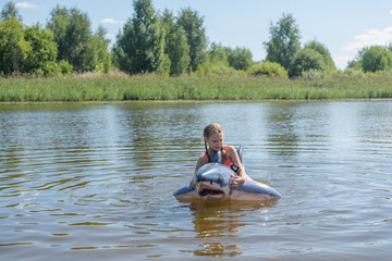 little boy swimming in the river on an inflatable shark