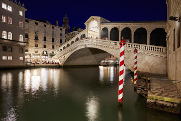 Rialto Bridge and Grand Canal with people and tourists at night in Venice, Italy