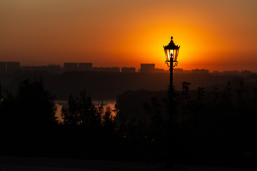 The dawn sun shining through the lantern. Dawn and an old lantern in the background