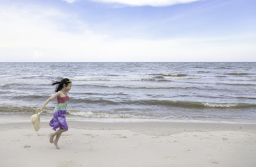 Fototapeta na wymiar Happy little girl playing on the beach,summertime fun concept