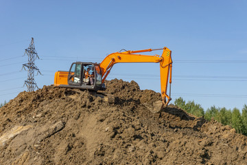 Obraz premium Orange excavator loads the land on a construction site..