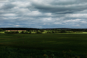 Fototapeta na wymiar Landscape with a field, a hills and dark clouds. 