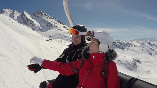 Two Funny Skiers Fooling Around Sitting On The Ski Lift In Winter Mountain