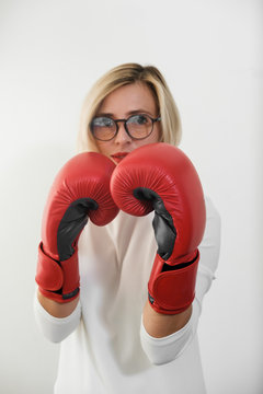 young woman with red boxing gloves. Girl in red dress are fighting, attacking and protecting.  Feminism, girl power, fight like girl, gender, woman rights. Focus on gloves. concept