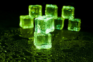 Green ice cubes on black background.