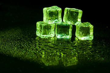 Green ice cubes on black background.