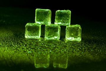 Green ice cubes on black background.