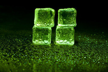 Green ice cubes on black background.