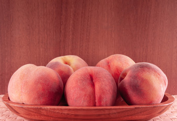 Five peach fruits in wooden plate