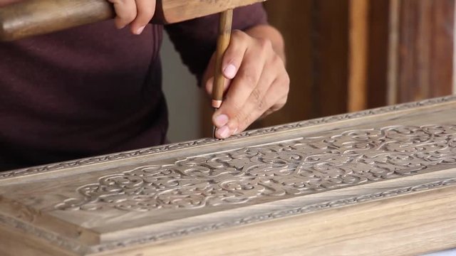 woodcarving, man carves the original ornament on a wooden board, Uzbekistan souvenir shop