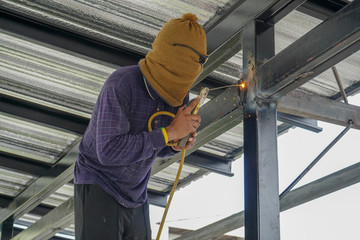 Welders are welding steel roof frame of home