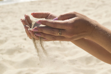 The sand is pouring from woman's hands.
