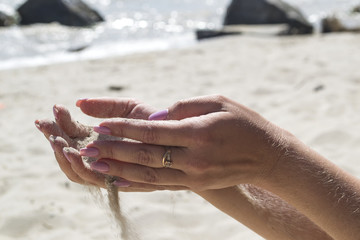The sand is pouring from woman's hands.