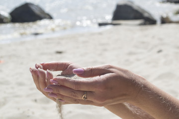The sand is pouring from woman's hands.