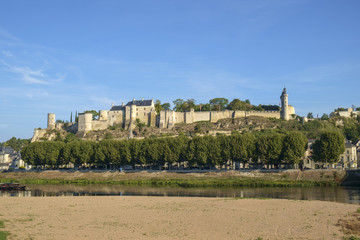 Fototapeta na wymiar Chinon chateau stands on the hill in early autumn morning sunshine high above the River Vienne, Indre-et-Loire, France. The river has much less water at the end of summer.