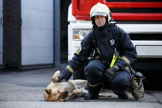 Photo of firefighter sitting squatting next to service dog at fire engine