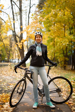 Photo of woman in helmet, jeans next to bicycle
