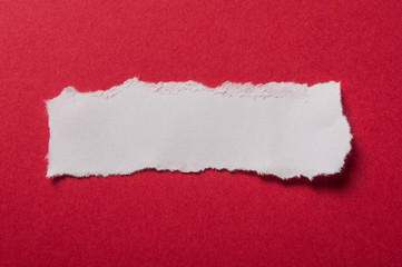 closeup of white torn paper on red paper background