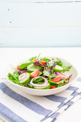 Vegetable salad with fresh lettuce, tomatoes and cucumber in white plate on white table