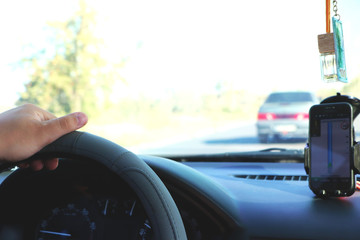 Man in the car and holding black mobile phone with map gps navigation, toned at sunset.