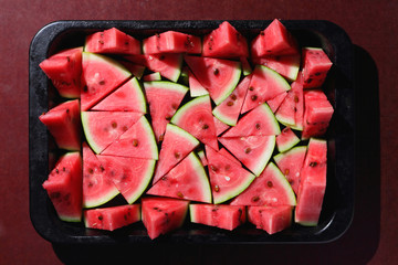 Pattern of watermelon slices. Pieces of ripe watermelon in old metal dishes. Red fruit with...