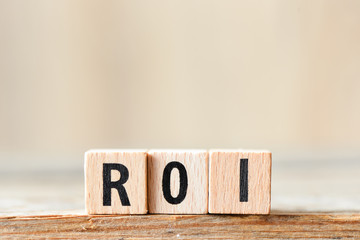 Return on Investment, ROI. Cube wooden block with alphabet building the word ROI.