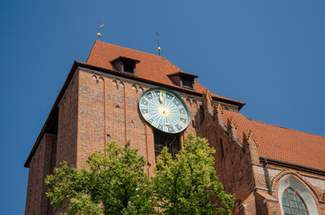 Big outside ancient clock on the Old Town Hall in Torun, Poland. Low angle view. Summer sunny day