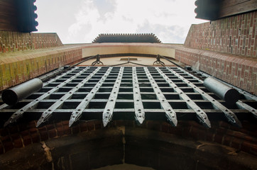 Gate in Castle of the Teutonic Order in Malbork, Poland. Red brick wall and metal lattice door.
