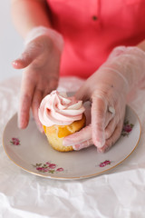 Obraz na płótnie Canvas Confectioner girl in gloves puts cream cake on saucer