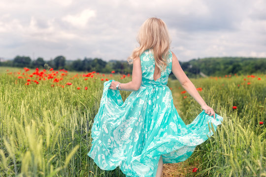 Little girl running away in a field whith poppy outdoors