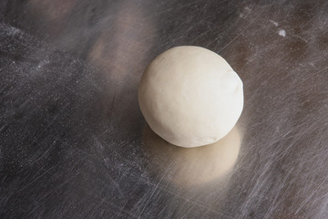 Fresh raw dough for pizza. Ball of pizza dough on steel table.