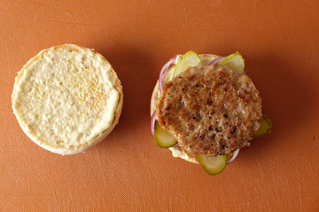 Making burger. Putting ingredients on bun.