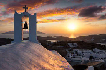 Romantischer Sonnenuntergang hinter einer orthodoxen Kirche mit Blick auf das Ägäische Meer und die Kykladen in Griechenland