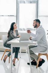 side view of patient and doctor talking in clinic with laptop on table
