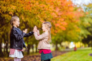 Obraz premium Little adorable girls at warm day in autumn park outdoors
