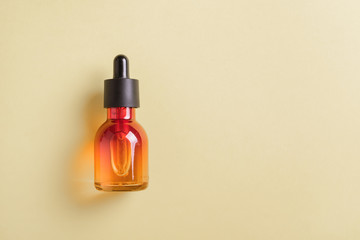 Glass bottle for cosmetics, serums and oils with a pipette on a yellow background.