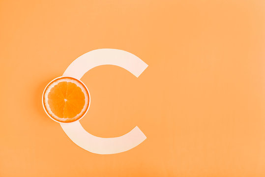 Orange and letter C on a yellow background. The concept of Vitamin C. Autumn protection against colds, antioxidant