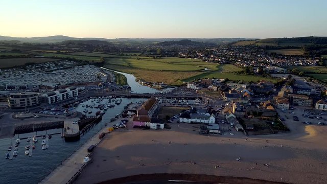 Drone rises above the beach and town of West Bay Dorset at sunset