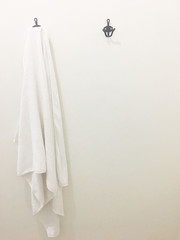 Clean and white towel is hanging on a hanger with concrete wall in the bathroom