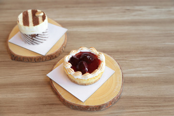 Strawberry tart pie and tiramisu cake on wooden plate.