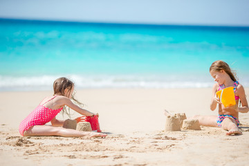 Two kids making sand castle and having fun at tropical beach