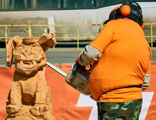 Experienced carpenter making a big wooden dog sculpture with a chainsaw