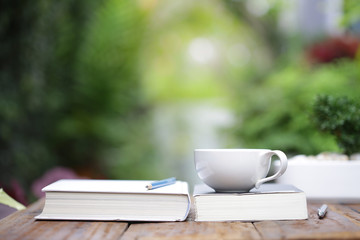 White coffee cup with notebooks on wooden table at outdoor